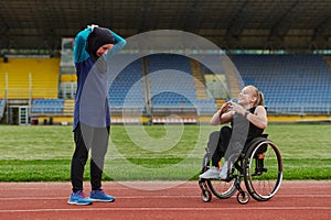 Two strong and inspiring women, one Muslim in a burka and the other in a wheelchair stretching necks while on the