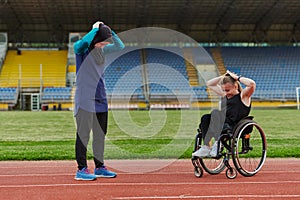 Two strong and inspiring women, one Muslim in a burka and the other in a wheelchair stretching necks while on the