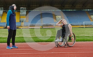 Two strong and inspiring women, one Muslim in a burka and the other in a wheelchair stretching necks while on the