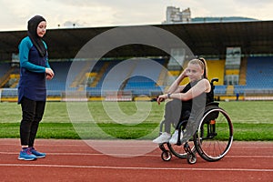 Two strong and inspiring women, one a Muslim wearing a burka and the other in a wheelchair stretching and preparing