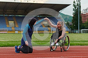 Two strong and inspiring women, one a Muslim wearing a burka and the other in a wheelchair stretching and preparing