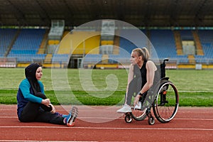 Two strong and inspiring women, one a Muslim wearing a burka and the other in a wheelchair stretching and preparing