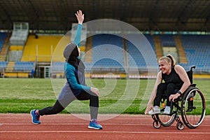 Two strong and inspiring women, one a Muslim wearing a burka and the other in a wheelchair stretching and preparing