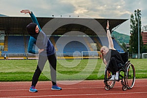 Two strong and inspiring women, one a Muslim wearing a burka and the other in a wheelchair stretching and preparing