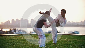 Two strong men show elements of capoeira wrestling on the grass in summer