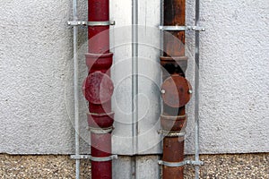Two strong rusted metal gutter rainfall pipes connected to lightning rod on both sides mounted on side of local apartment building