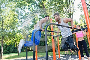 Two strong young men doing dips exercise for the upper body outdoors