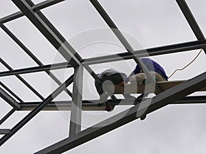 Two structural steel workers working on a high rooftop for a house roof structure installation
