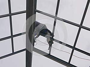 Two structural steel workers working on a high rooftop for a house roof structure installation