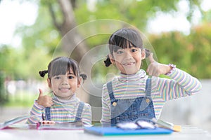 Two student little Asian girls reading the book on table