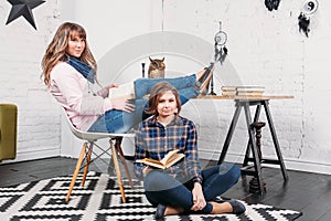 Two students doing homework together and helping each other sitting in a table at home with a homey background