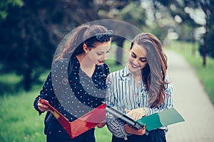 Two students learning reading a notebook and commenting in the street