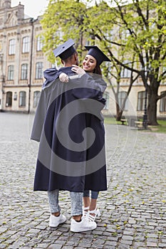 Two students in mortarboards hugging
