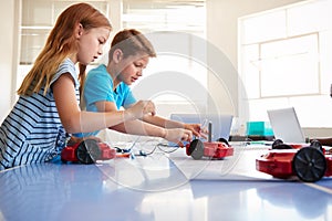 Two Students In After School Computer Coding Class Learning To Program Robot Vehicle