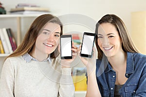Two students showing to camera smart phone screens