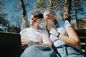 Two students studying on a laptop in a sunny park setting
