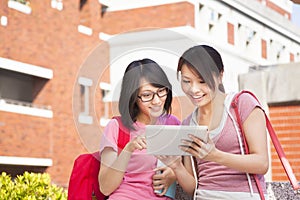 Two students using a tablet to discuss homework