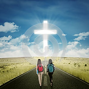 Two students walking toward a cross