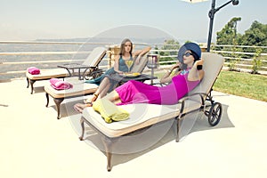 Two stylish girls sitting on beach chairs enjoying the tropical weather