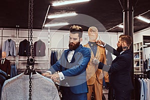 Two stylish shop assistants elegantly dressed working in a menswear store.