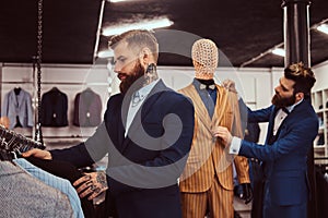 Two stylish shop assistants elegantly dressed working in a menswear store.