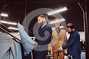 Two stylish shop assistants elegantly dressed working in a menswear store.