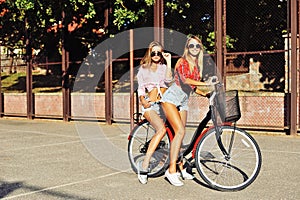 Two stylish young and girls on a bicycles in the summer