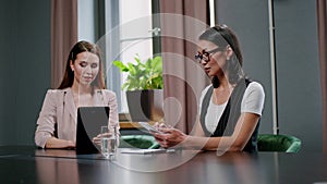 Two successful businesswomen at meeting in conference room.