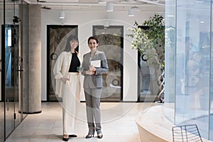 Two successful elegant businesswomen in formal suits pose in office