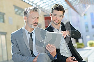 two suited men looking at digital tablet