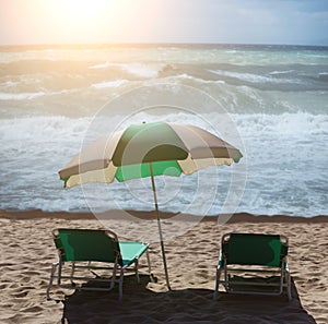 Two sun loungers and an umbrella on a sandy beach by the sea