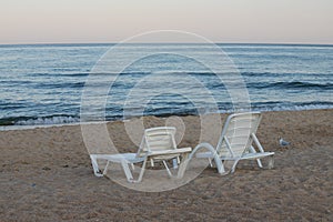 Two sunbeds on a sandy calm beach with turquoise sea water and white sand