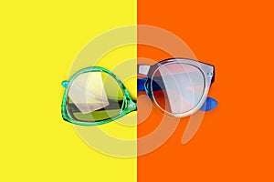 Two sunglasses yellow orange red background closeup top view fashion man and woman sunshades