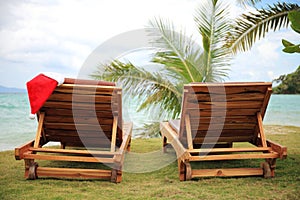 Two sunloungers with Santa hat standing on a beach photo