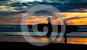 Two surfers on Piha Beach in sunset