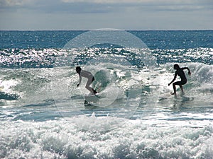 Two surfers riding a wave.