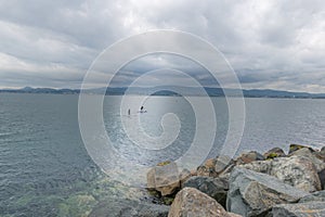 Two surfers are swimming on a surfboard in the waters of Dublin bay.