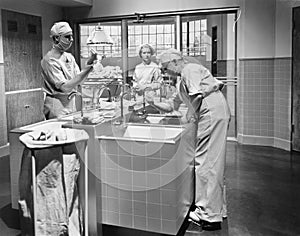 Two surgeons and a nurse in the scrub room preparing for an operation