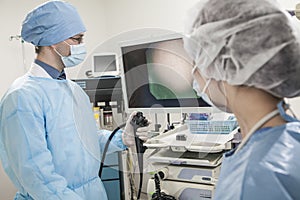 Two surgeons preparing for surgery, looking at medical equipment