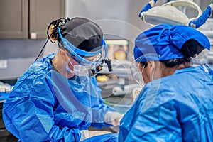 two surgeons in scrub suits and sterile gear preparing for surgery