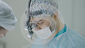 Two surgeons work together in operating room. Action. Couple of professional surgeons during operation. Bright operating