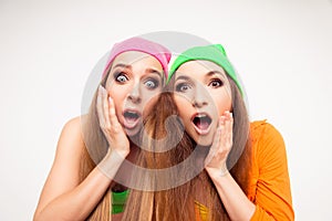 Two surprised girls with open mouth touching their faces