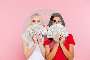 Two surprised women hiding behind the money