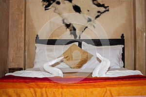 Two swans made of towels on bed in honeymoon suite colorful room hotel decorated for wedding or just married people