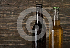 Two sweating, cold bottle of beer on dark wooden background