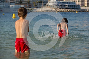 Two sweet children, splashing each other with water on the beach