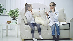 Two sweet kids playing with teddy-bear. The girl who plays a doctor is examining plush bear with stethoscope.