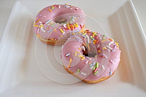 Two Sweet Pink Donuts Served on a Square White Plate