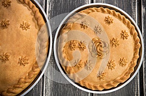 Two sweet potato pies with edible decorations on top standing on the wooden table