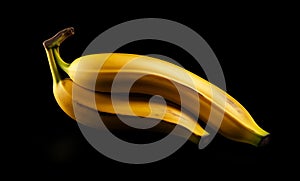 Two sweet ripe yellow bananas together are isolated against a black background in close-up.